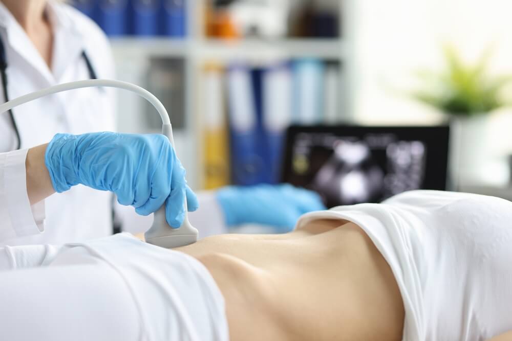 A female doctor taking an ultrasound of woman’s lower stomach.