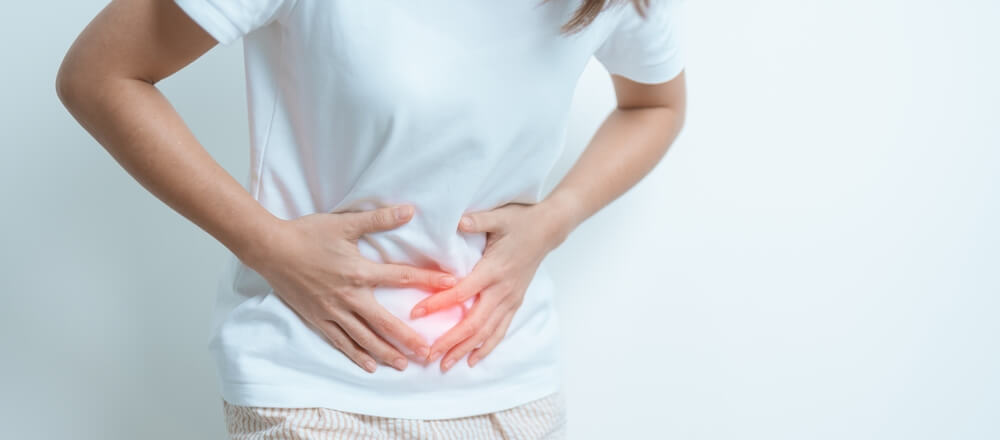 A woman with painful fibroids holding her lower stomach