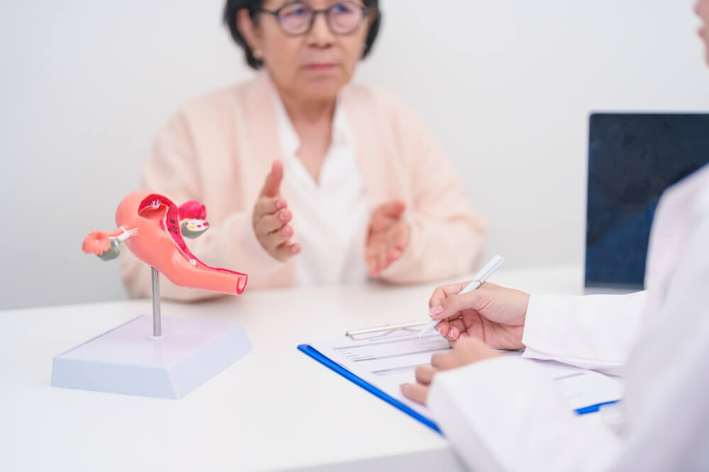 Elderly Woman patient consulting doctor with anatomy Uterus and Ovaries.