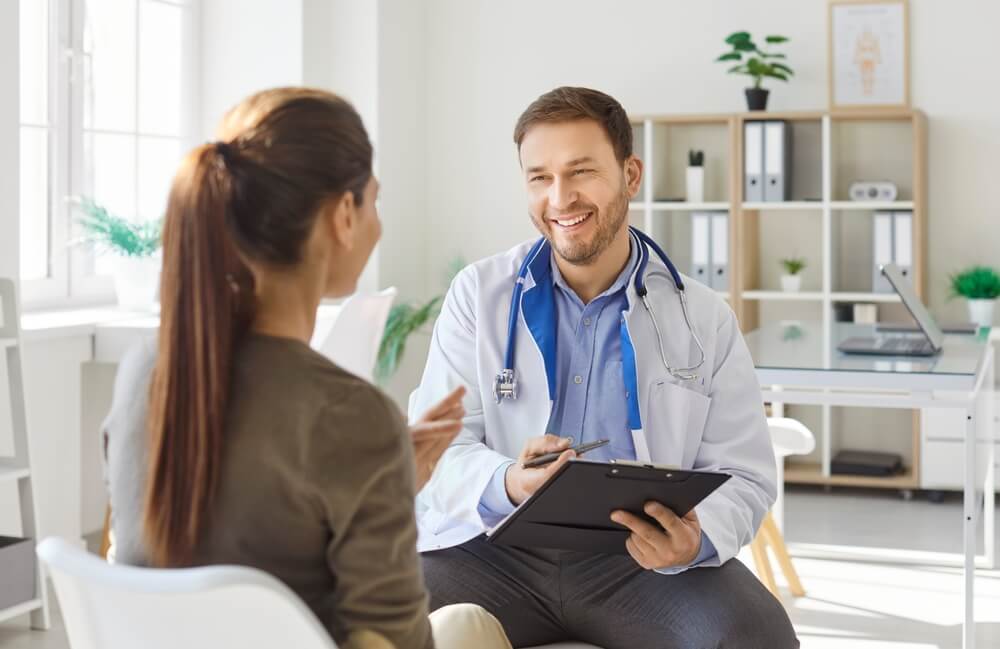 Female patient comes on doctors appointment, getting medical advice, having pleasant conversation with physician, talks about complaints posing in clinic office. Healthcare visit.