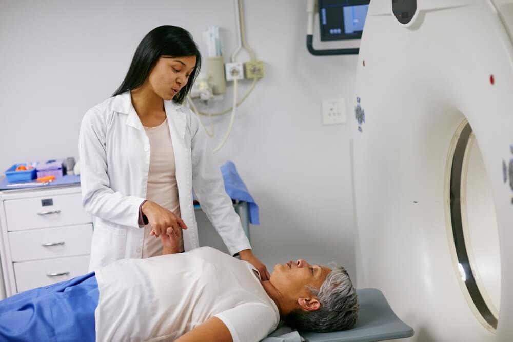 Mri, doctor and woman holding hands of patient in hospital before scanning in machine. Ct scan, comfort and medical professional with senior female person in radiology test for healthcare in clinic.