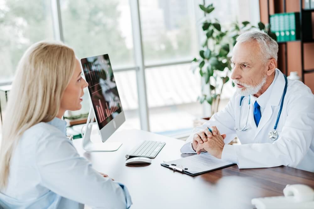 Senior doctor discusses health concerns with a young woman during an office consultation.