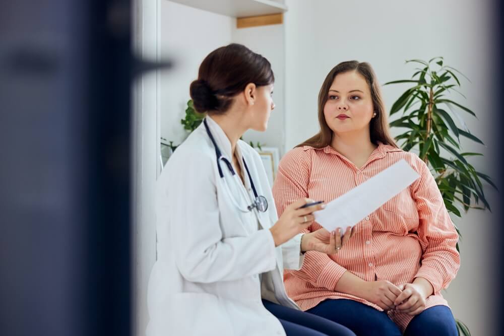 A serious woman is sitting with her female doctor, discussing health goals.