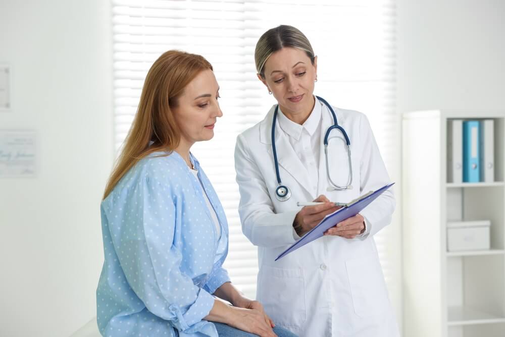 Smiling cardiologist showing clipboard to patient in clinic